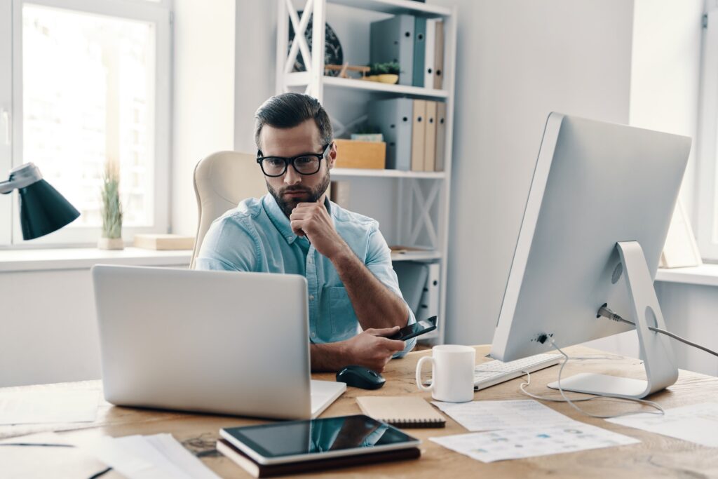 Working with numbers. Young modern businessman working using computer while sitting in the office