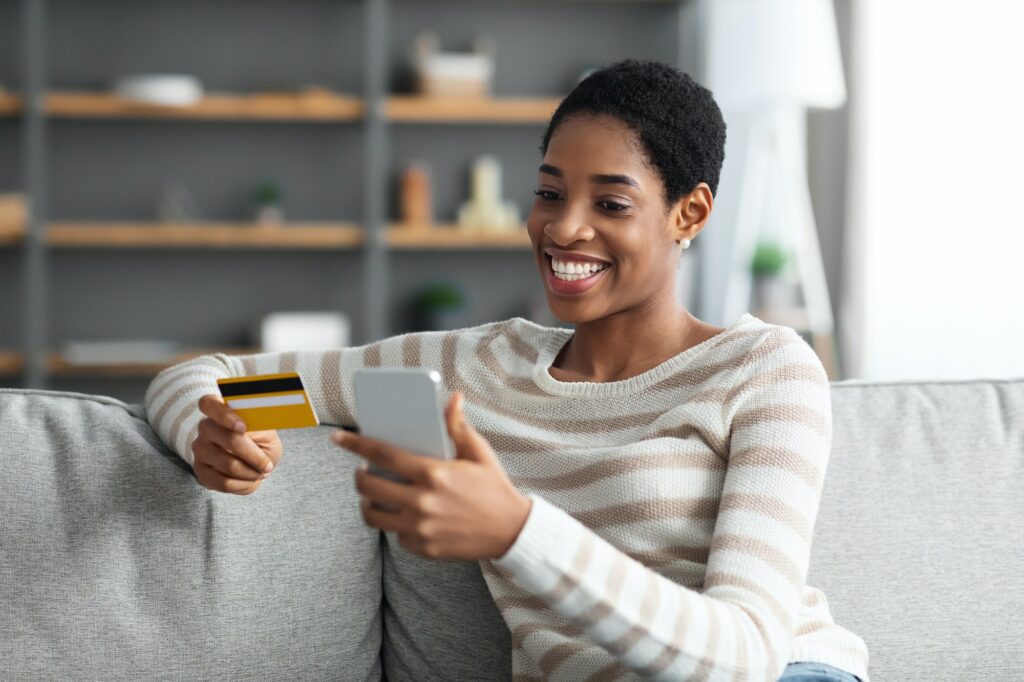 Fast Money Transfers. Smiling Black Female With Smartphone And Credit Card