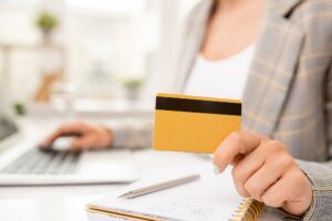 Yellow credit card with black magnet line held by contemporary businesswoman