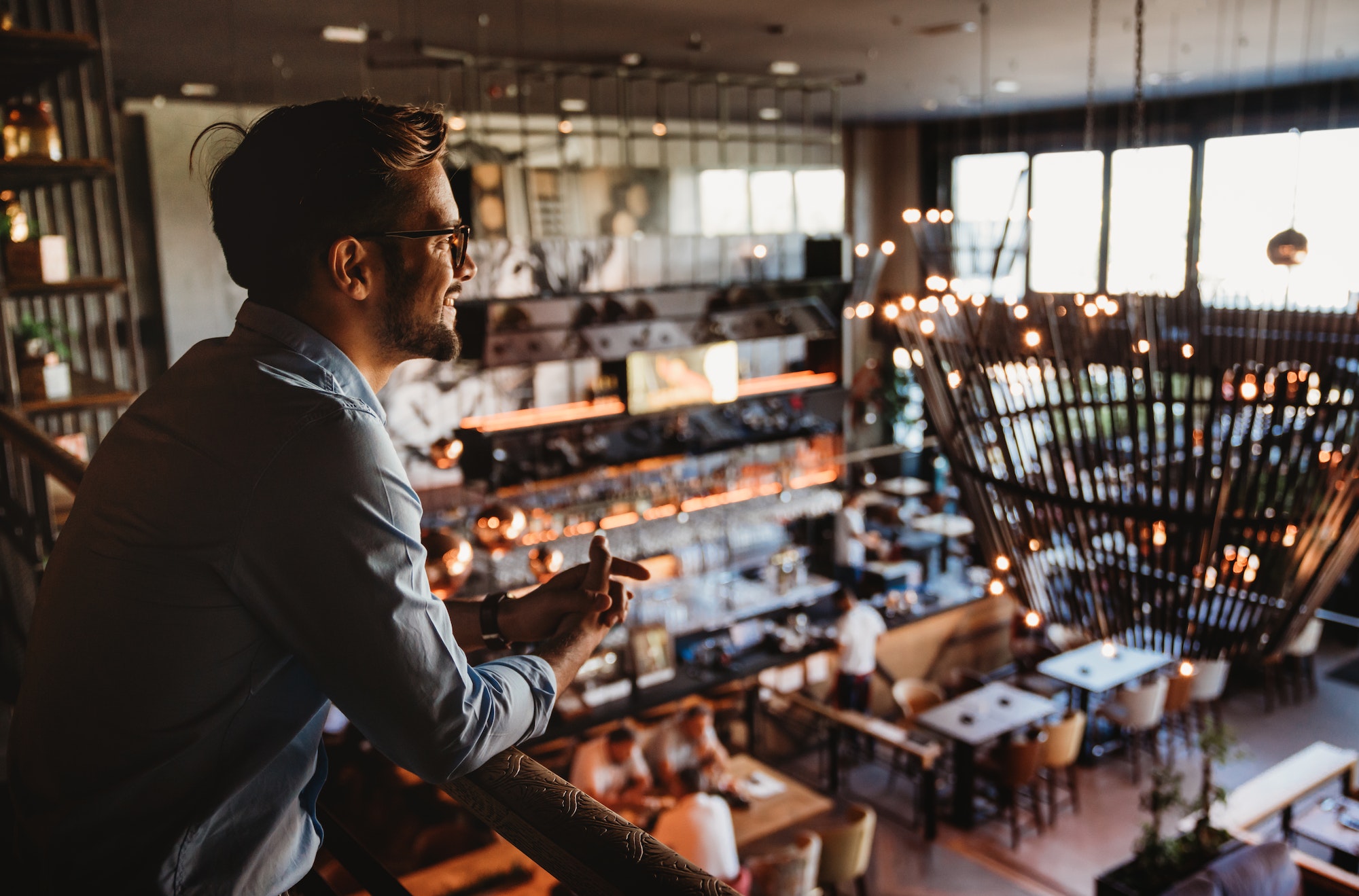 Happy businessman, restaurant owner proudly looking at crowded restaurant